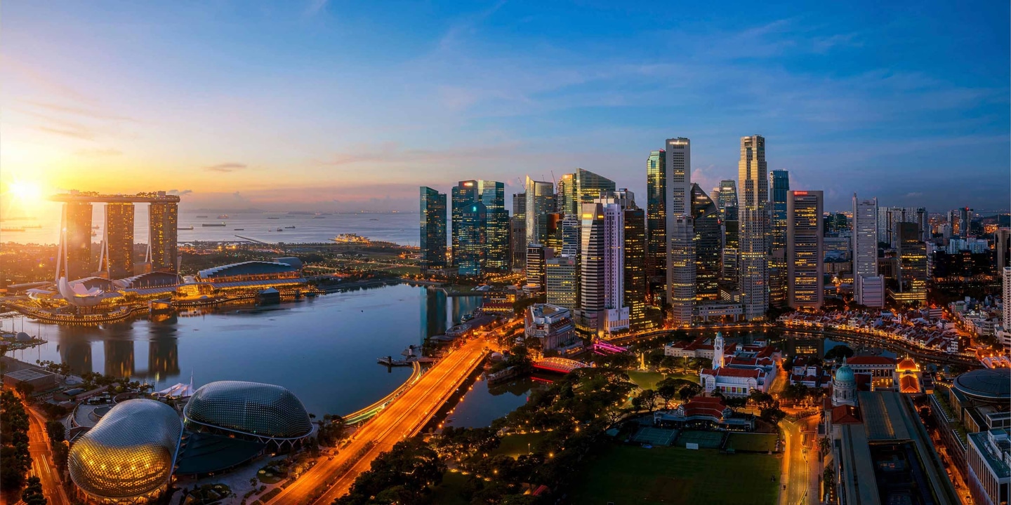 Singapore skyline at sunrise, with high-rise buildings and the streets below with an orange glow