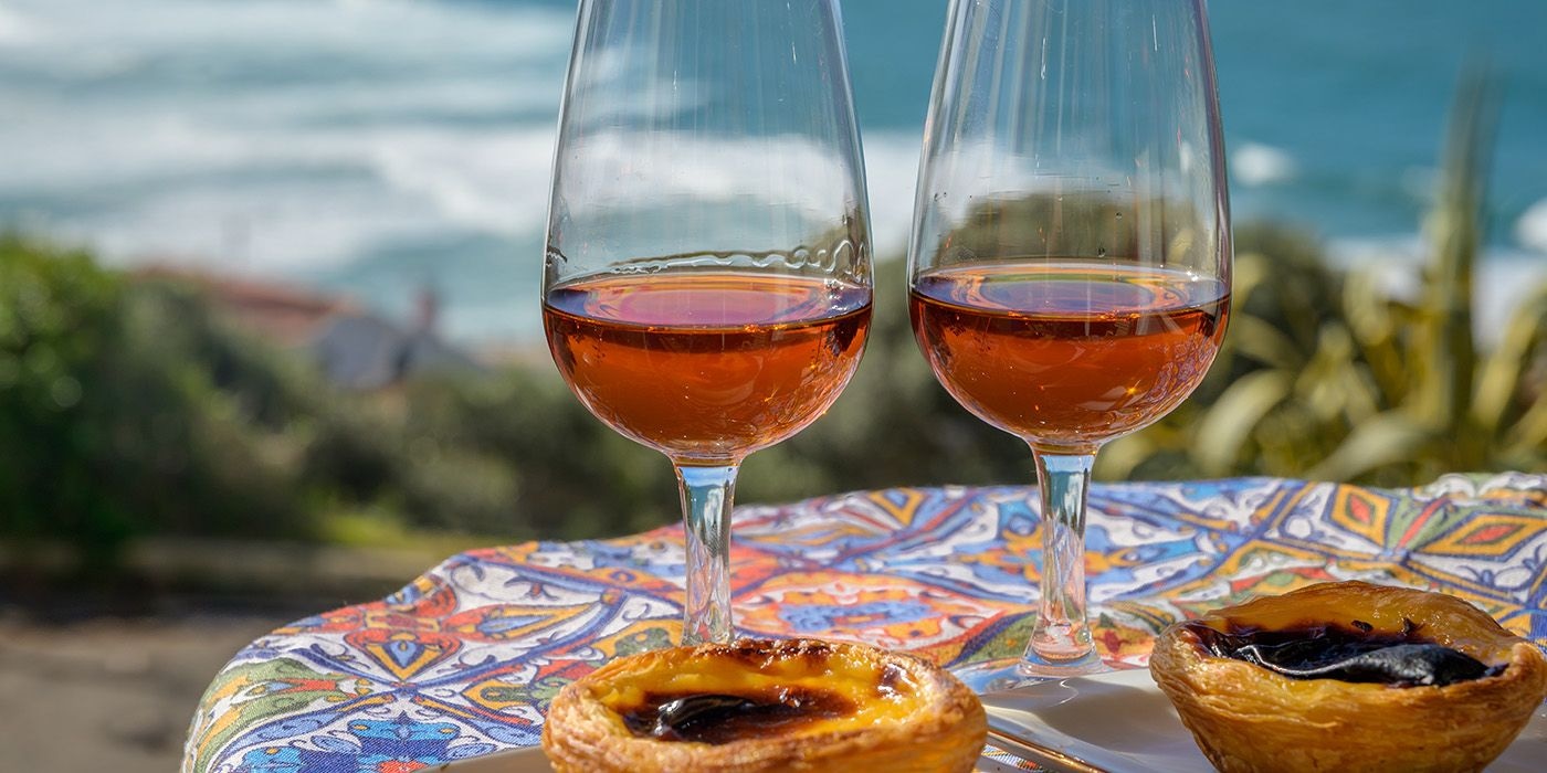 Two glasses of port wine and pastéis de nata overlooking the ocean